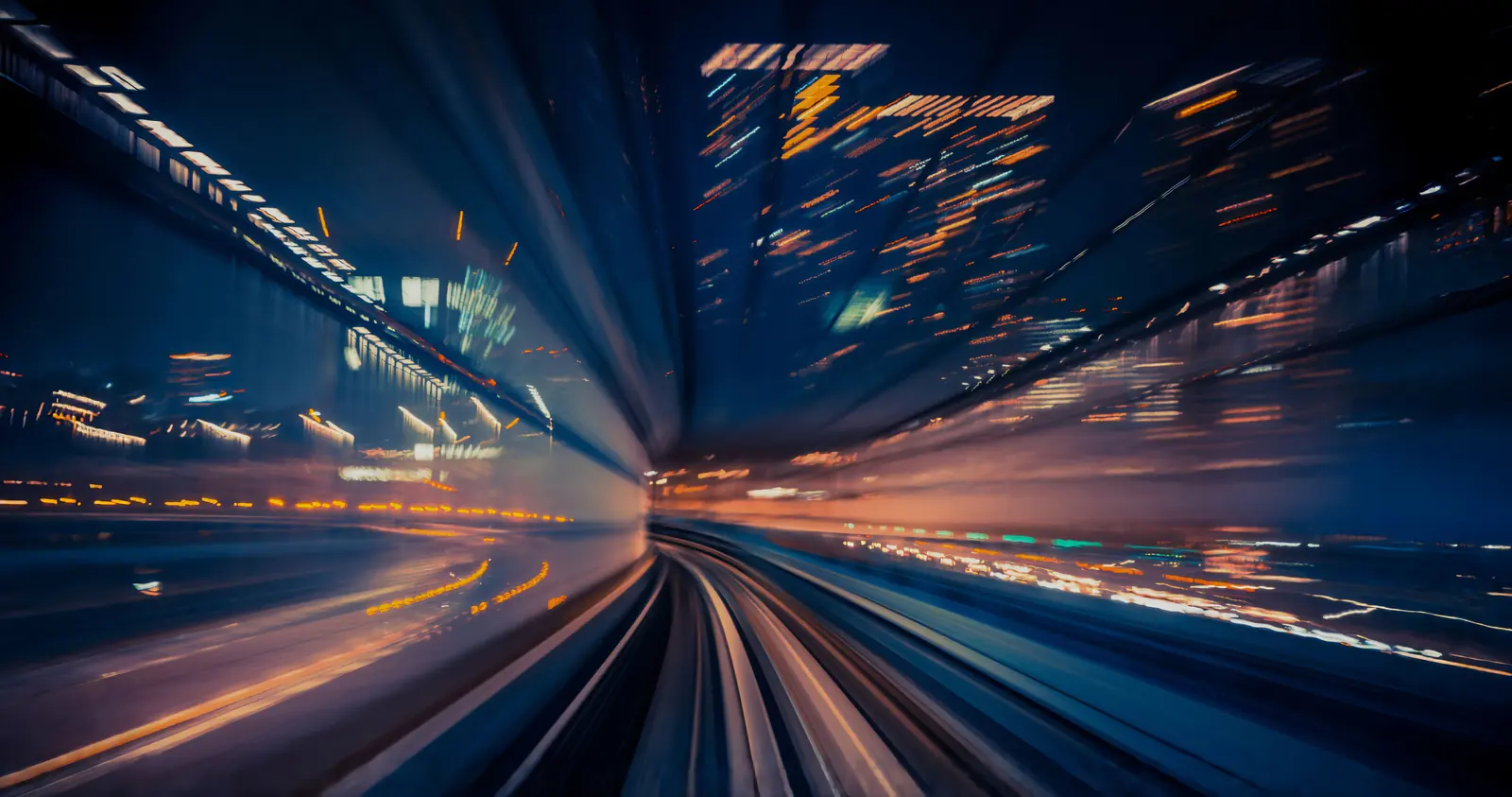 A long exposure taken from a moving train at night, city lights and track drawn into streaks that converge on a point ahead.