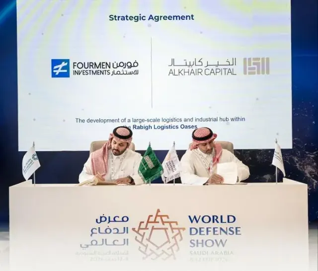 Fourmen Investments and Alkhair Capital signing a strategic agreement at the World Defense Show, beneath a screen reading “The development of a large-scale logistics and industrial hub within the Rabigh Logistics Oases”.